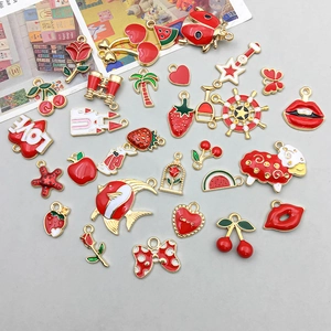 Detailed flat lay of red enamel fruit and heart charms for DIY jewelry making