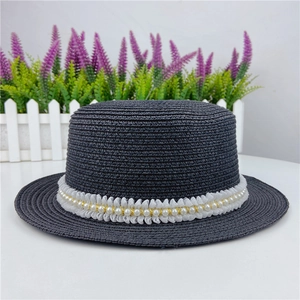 Détail d'un chapeau de paille à sommet plat avec dentelle élégante et ruban de perles