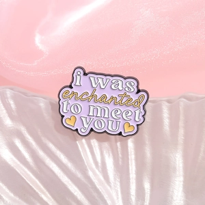 Purple enamel brooch with i was enchanted to meet you text and heart motif on fabric