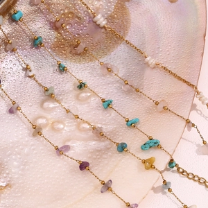Detailed macro of 18K gold chain with natural crushed stones and pearls on shell