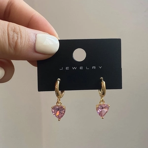 Detail of pink heart zircon pendant earrings with golden hoops on display card