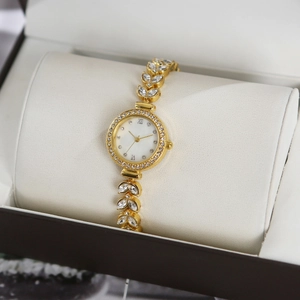 Close-up of a gold luxury watch with leaf-shaped gemstone links in a gift box