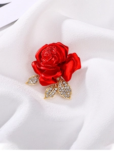 Macro shot of red rose brooch with golden leaves and sparkling crystal rhinestones