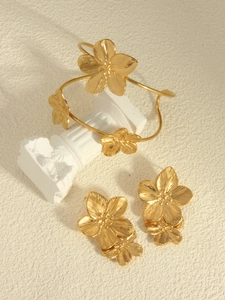 Detailed macro shot of a 18k gold-plated floral jewelry set with bangle and earrings