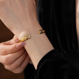 Detail of gold-plated stainless steel cuff with cubic zirconia on black velvet background