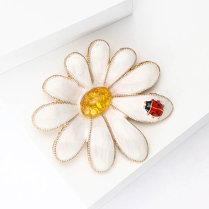 Creative enamel daisy brooch with amber gemstone core and red ladybug on white background