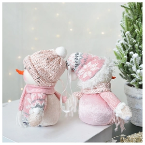 Pink plush snowman figures with sequined hats on books for cozy Christmas decor