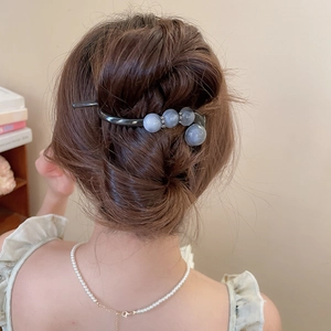 Detailansicht einer eleganten schwarzen Haargabel mit Marmorperlen in einem Dutt gestylt