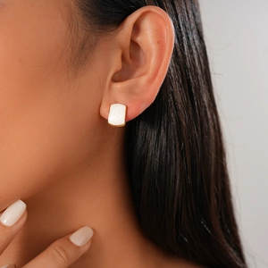 Close-up of elegant gold rectangular earring with pearl inlay worn by a model