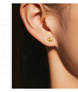 Close-up of yellow floral earrings with enamel finish and a center zircon on ear