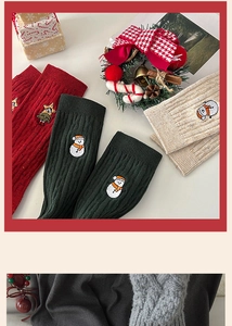 Flat lay of cable knit Christmas crew socks with snowman embroidery and festive ornaments
