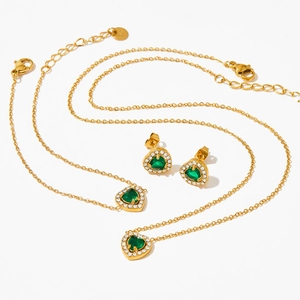 Golden stainless steel heart jewelry set with green zircon stones on white background
