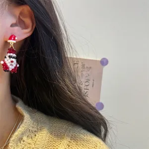 Close-up of handmade beaded Christmas Santa earrings worn by a model in warm light