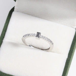Detail of silver plated letter ring with zircons in a green and white jewelry box
