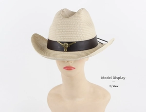 Close-up of beige straw cowboy hat featuring a brown band and metal bull head ornament