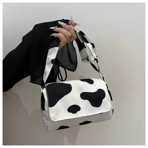 Close-up of stylish cow print shoulder bag with matching patterned wide strap for women