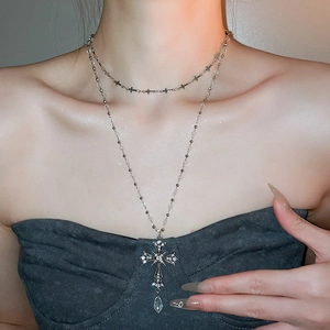 Detail of double-layer crystal cross necklace with sparkling rhinestones and teardrop pendant