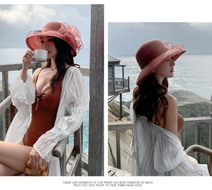 Detail of wide brim burgundy beach hat with organza floral accent on seaside balcony
