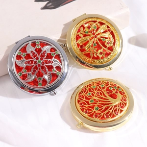 Three vintage hollow metal compact mirrors with rhinestone floral, dragonfly, and peacock designs