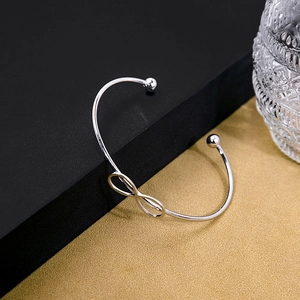 Detailed view of silver infinity knot bangle with polished metallic finish on sleek surface