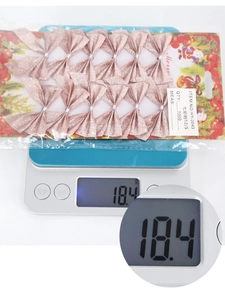 Glittery pink Christmas bows set of 12 weighed on electronic scale in packaging