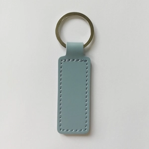 Detail of gray-blue rectangular PU leather keychain with neat stitching and silver metal ring
