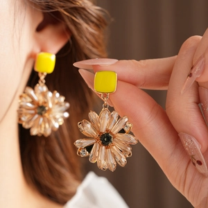Detailansicht goldener Gänseblümchen-Ohrringe mit Kristallblüten und dunklen Edelsteinen