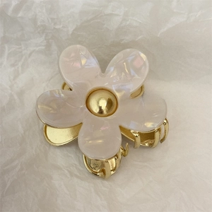 Macro detail of acetate flower hair claw with gold metal finish and pearl-like petals