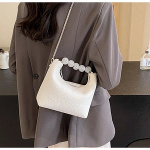 Detailed back view of a white pebble leather mini handbag with a large pearl handle and chain