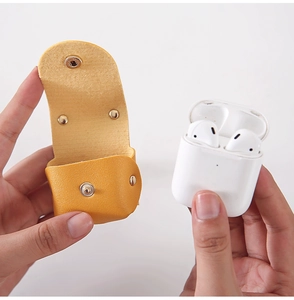 Close-up of a yellow textured leather AirPods case with a metal snap button and strap