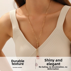 Detailed view of long gold-plated stainless steel necklace with brown teardrop pendants