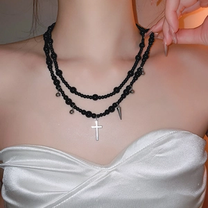 Detail of Y2K double-layer black beaded necklace with silver cross and spike pendants