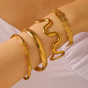 Detail of four vintage gold stackable bangles featuring textured geometric and eye motifs