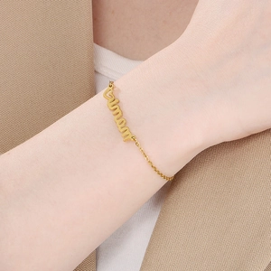 Close-up of gold MAMA Amour cursive letter bracelet with diamond accents on a model wrist