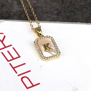 Macro shot of 18K gold letter K rectangular pendant with shell inlay and zircon frame