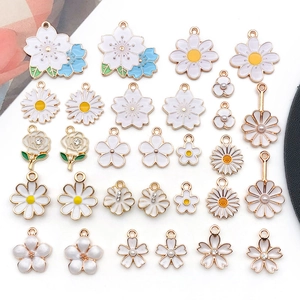 Flat lay of mixed white enamel flower charms with pearls and crystals for DIY jewelry