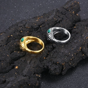 Creative snake head rings in gold and silver with green gem eyes on dark textured stone