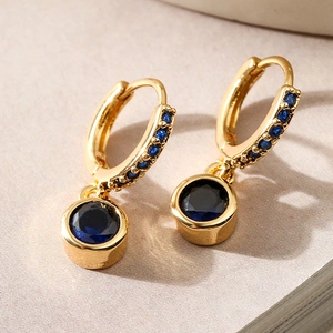 Minimalist gold plated copper drop earrings featuring blue zircon gems on a soft beige background