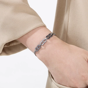 Close-up of minimalist silver rectangular link bracelet worn with a camel blazer
