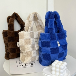 Three plush checkerboard tote bags in brown, beige, and blue displayed on a desk