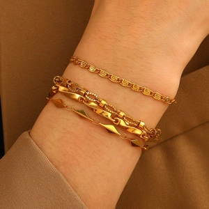 Detail of four stacked gold-plated stainless steel chains on wrist with elegant textures