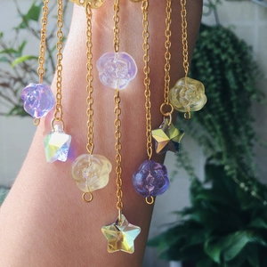 Close-up of golden arm chain with iridescent butterfly and rose pendants in sunlight