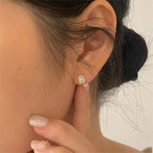 Close-up of elegant silver geometric stud earring with rectangular zircon on model