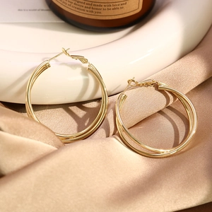 Detailed view of large gold double hoop earrings on silk display with soft warm lighting