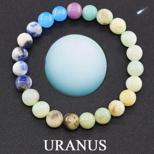Detail of Uranus themed beaded bracelet with colorful natural stones on black space background