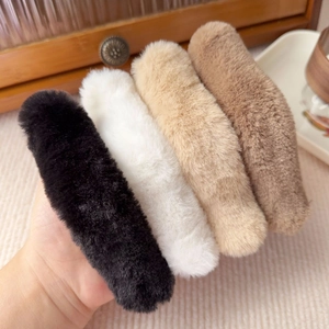 Set of four plush duckbill hair clips in black, white, and brown shades held in hand