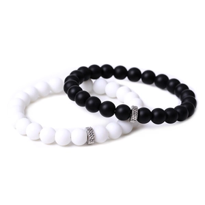 Detailed view of matte black and white beaded bracelets for couples with silver spacers