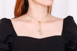 Detailed view of a gold Y-shaped necklace with colorful enamel ball pendants on a model