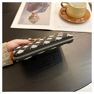 Macro side view of a textured long wallet featuring a cross-pattern weave and gold zipper