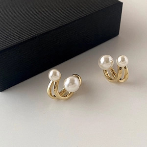 Elegant gold U-shaped pearl earrings with dual white pearls on a minimalist background